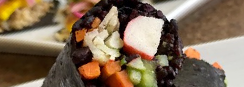 Black sushi roll topped with vegetables