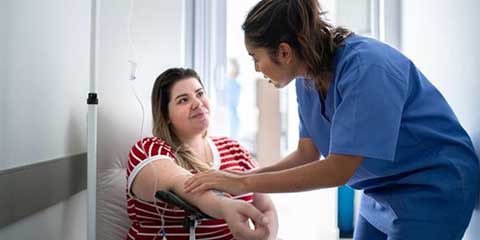 Nurse checking on a patient sitting on a hospital bed