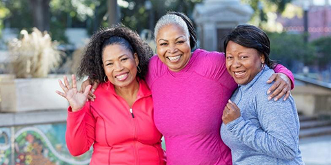 Three smiling women standing together with arms around each other