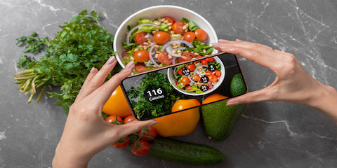 Hands holding a bowl of healthy food beside a smartphone with a nutrition app