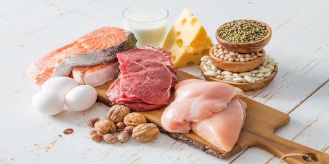 Protein foods including fish, chicken, cheese and beans on a cutting board
