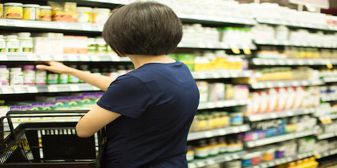 Woman reading a product label in a grocery store aisle
