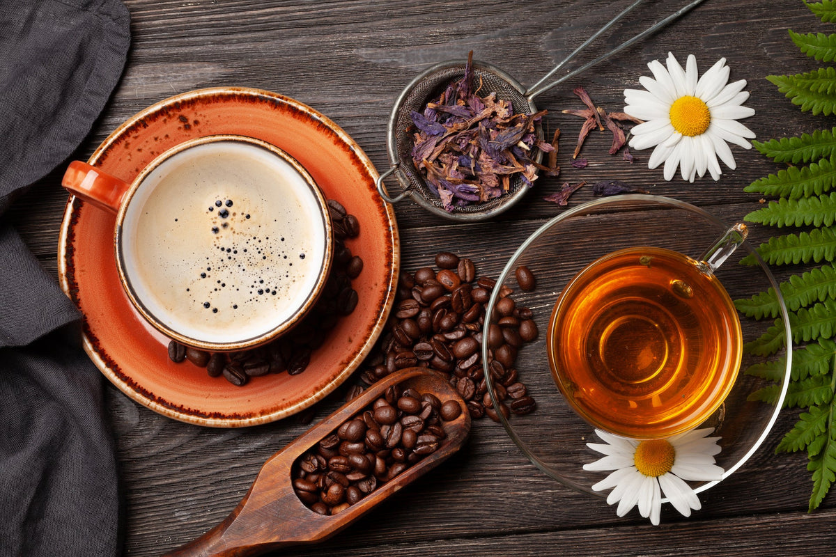 Cup of coffee and a mug of tea surrounded by coffee beans and loose tea
