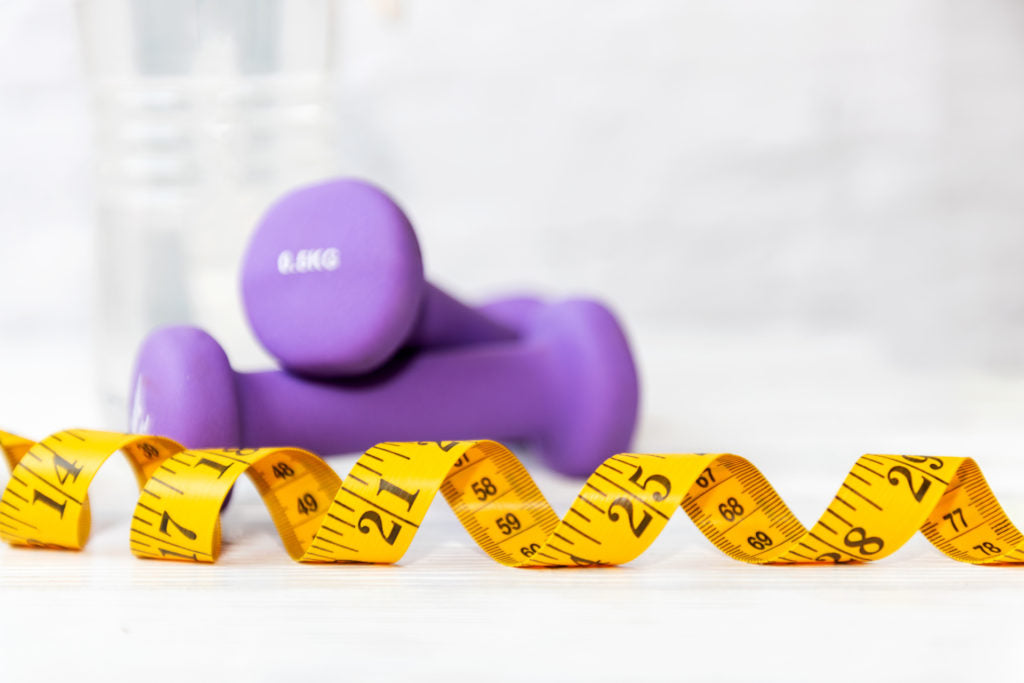 Purple dumbbells beside a yellow measuring tape