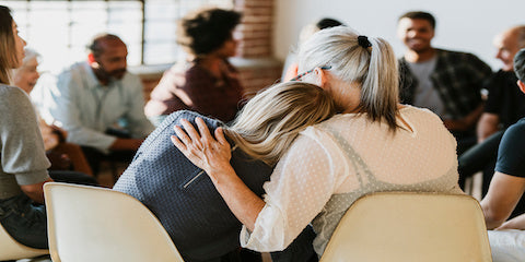 Support group of people sitting in a circle comforting one another