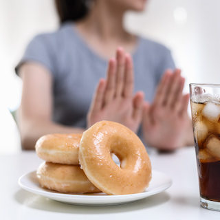 Woman holding up her hand to refuse a plate of donuts