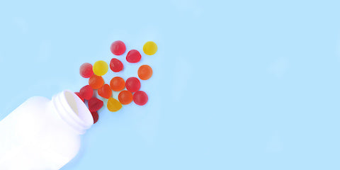 Colorful gummy vitamins spilling from a white bottle