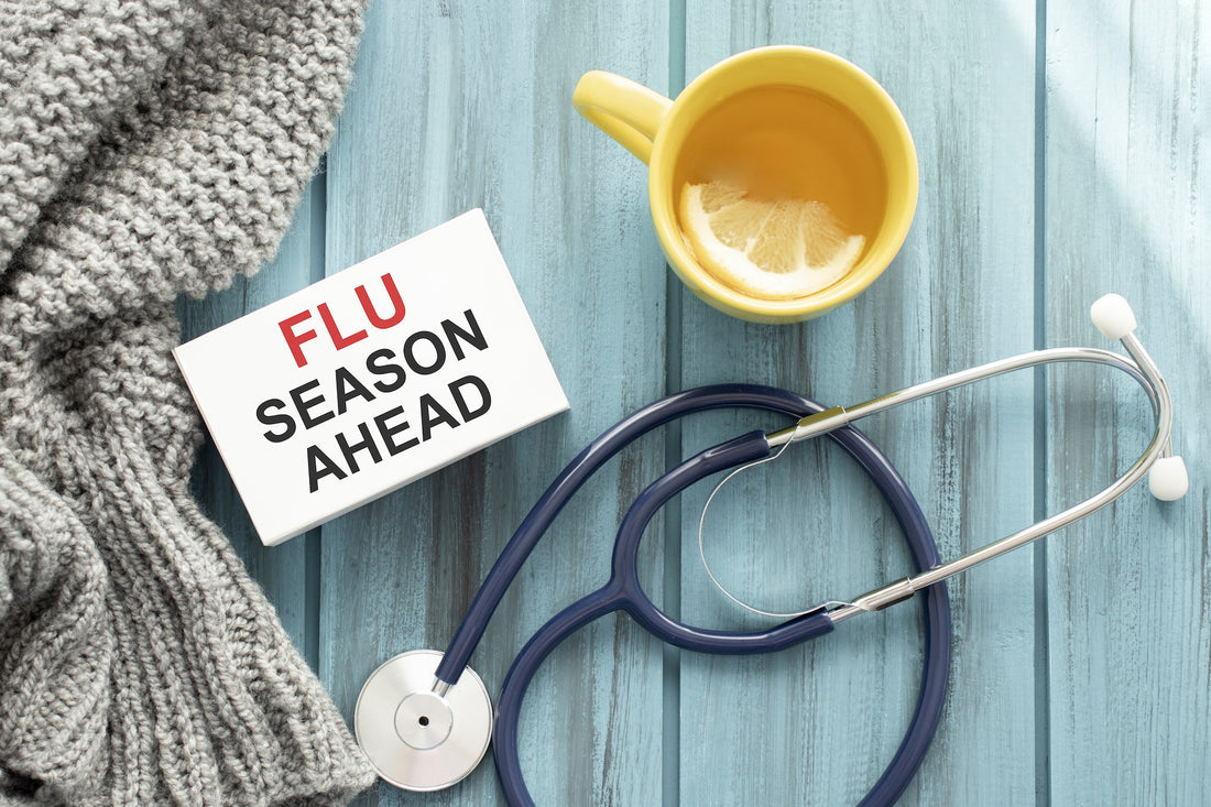 Flu season ahead note beside a stethoscope, scarf and mug of tea