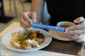 Woman eating dinner, holding Ozempic injector, wondering, “Is Ozempic a GLP-1?