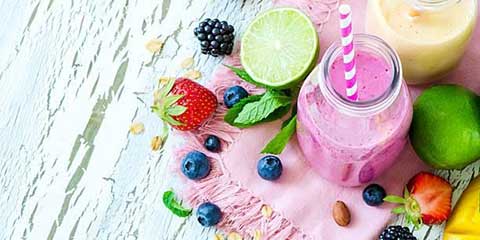 Smoothies and fruit on a white wooden table