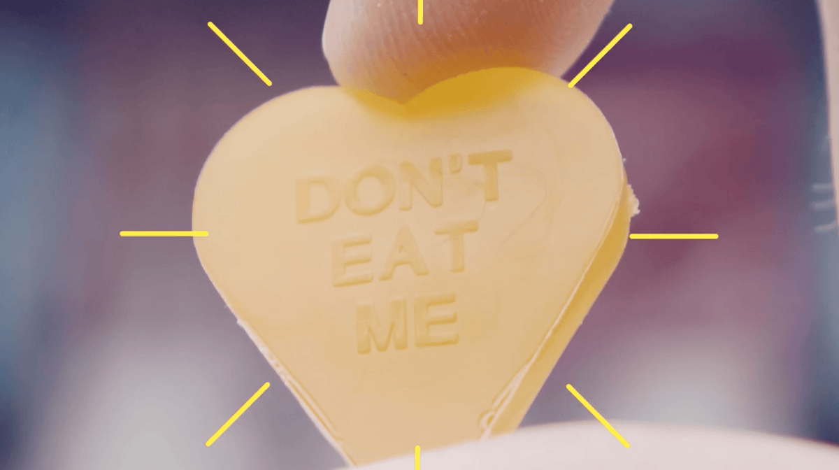 Hand holding yellow Don't Eat Me candy heart
